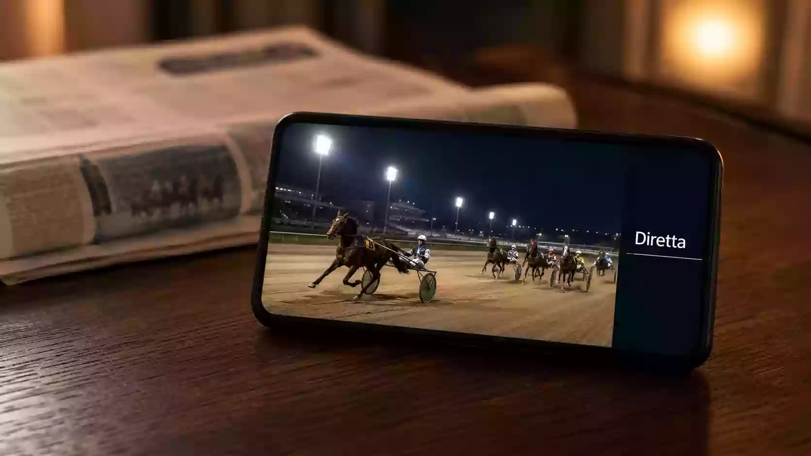 Smartphone con streaming live di una corsa di trotto sull'app di un bookmaker italiano